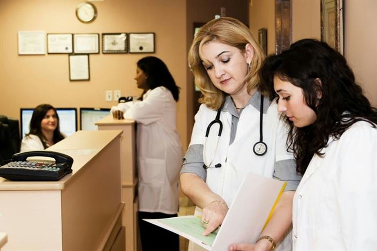 Two clinicians reviewing a paper form together at a clinic front desk